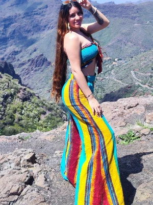 Färgglatt set med bandeau och byxor - Säljer ett färgstarkt set från Cider med bandeau-topp och utsvängda byxor. Setet har breda ränder i turkos, gul, röd och lila samt knytning framtill på toppen. Materialet ser ut att vara lätt och luftigt, perfekt för varma dagar. Jag säljer setet eftersom byxorna är för långa för mig; jag är 1,62 meter lång.