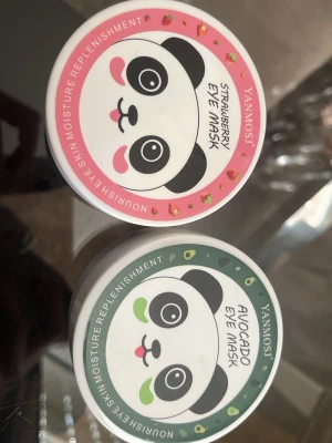 YANMOSI ögonmasker jordgubb & avokado - Två burkar ögonmasker från YANMOSI, en med jordgubb och en med avokado. Båda har gulligt pandamotiv på locket och färgglada detaljer – rosa för jordgubb och grön för avokado. Perfekt för återfuktning och fräsch känsla under ögonen.