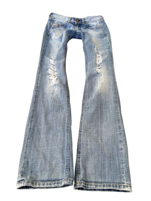 Ljusblå bootcut jeans från Diesel - Säljer ett par ljusblå bootcut jeans från Diesel med slitna detaljer och snyggt tvättad look. Jeansen har låg midja! Innerbenslängd 86 och midjemått 38