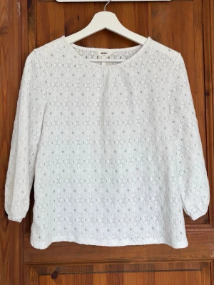 Vit spetsblus  - Söt vit spetsblus från Object med rund halsringning och trekvartsärm. Blusen har ett diskret mönster i spetsmaterial som ger en romantisk och fräsch känsla. Perfekt att matcha med jeans eller kjol för en trendig look.
