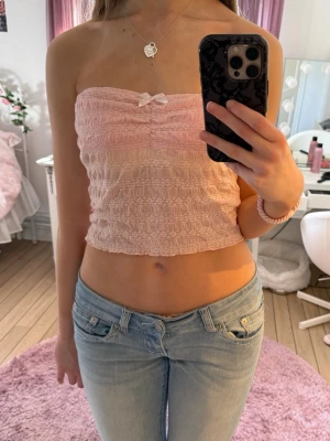 Rosa tubtopp - Så söt rosa bandeu topp med rosett🎀Köpte från Plick för några år sedan men endast använd fåtal gånger. Det står ingen lapp men skulle säga att den passar S eller XS med större byst bäst men funkar även på M då den är stretchig. Den är inte lika beige som den ser ut i de sista bilderna