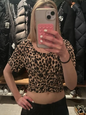 Leopardmönstrad topp med knyte - Säljer en croppad topp med leopardmönster och knyt i midjan. Toppen har korta ärmar och rund halsringning och en knut som man kan knyta om. Tröjan köptes för två år sedan från Victorias secret lappen är kvar💗den kostade ca 350kr
