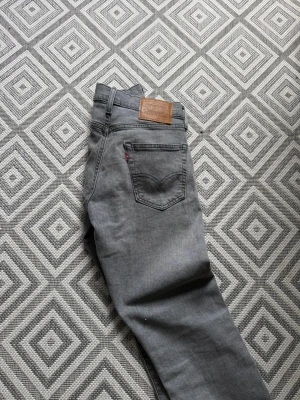 Grå jeans från Levi's - Snygga grå jeans från Levi's med klassisk femficksmodell och rak passform. Jeansen har en läderpatch bak i midjan och den ikoniska röda Levi's-taggen på bakfickan. Tillverkade i mjukt denimtyg som ger en skön känsla och stilren look.