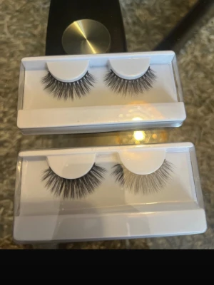 Svarta volymfransar 20kr/styck. - Två förpackningar med svarta lösögonfransar i volymmodell. Fransarna är täta och fluffiga med en naturlig böj, perfekta för att ge ögonen ett extra lyft. Kommer i genomskinlig plastförpackning med vit botten. Materialet ser ut att vara syntetiskt.