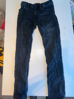 Mörkblå slim jeans Jack & Jones - Snygga mörkblå slim fit jeans från Jack & Jones, modell Glenn. Klassisk femficksdesign med dragkedjegylf och bälteshällor. Jeansen har en smal passform och är tillverkade i ett mjukt denimtyg som sitter skönt hela dagen.