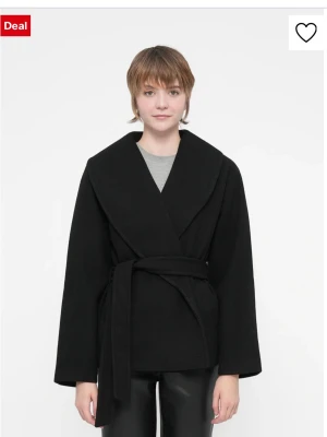 Svart kappa med knytskärp veromoda  - Stilren svart kappa med bred sjalkrage och knytskärp i midjan. Kappan har en rak passform och är tillverkad i ett mjukt tyg som ger en clean look. Perfekt för dig som gillar minimalistisk stil och vill ha en enkel men snygg jacka.