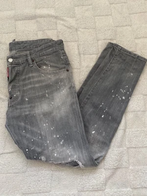 Dsquared2 Jeans - Hej! Säljer ett par Dsquared2 Jeans i färgen grå. Väldigt mycket detaljer på som sticker ut även vänligt raka i storleken.  Skick 9,5/10 Storlek 48 motsvarar 30-32 ungefär folk som bär S/M . Hör av er för mer info ///
