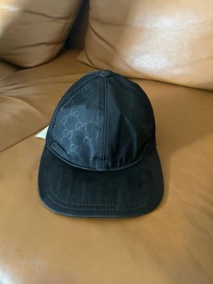 Svart keps från Gucci med meshdetaljer - Säljer min svarta Gucci keps nylon för 1300 pris kan diskuteras storlek S den har en liten skada som man kan se på en bilden men man ser inte det så mycket 
