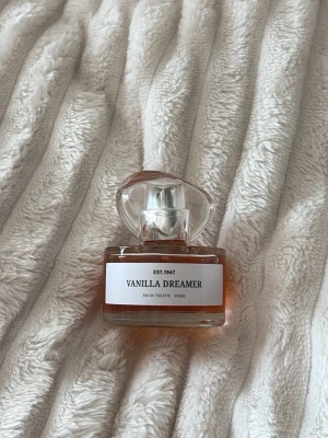Vanilla Dreamer Eau de Toilette - Vanilla Dreamer från EST.1947 är en Eau de Toilette med en söt och mjuk doft av vanilj. Flaskan är genomskinlig med rundade former och har ett elegant, klart lock. Parfymen är vegansk och har en varm, bärnstensfärgad vätska som syns genom glaset. Använt fåtal gånger. 💛liten extra gåva vid varje köp! Skickar allt omsorgsfullt i bubbelplast & kartong