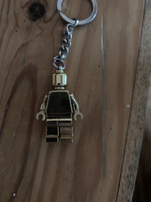 Guldig LEGO-figur nyckelring - Säljer en cool nyckelring med en guldig LEGO-figur. Perfekt att hänga på väskan eller nyckelknippan för en unik touch. Figuren är helt i metall-look och har den klassiska LEGO-designen. Ett måste för LEGO-fans eller dig som gillar snygga accessoarer.