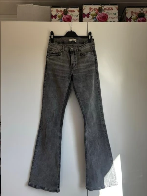 Grå bootcut jeans  - Säljer ett par grå bootcut jeans med klassisk femficksmodell och hög midja. Jeansen har en snygg tvättad look och är tillverkade i ett mjukt denimtyg. Perfekta för dig som gillar retrostil och vill ha ett par jeans med lite vidare ben.