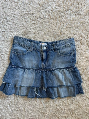 Blå jeanskjol med volanger - Såååå snygg blå jeans kjol med volanger. Den är från Gina Young och passar perfekt för dig som gillar en avslappnad och trendig stil. Den är sparsamt använd 🍒💖 