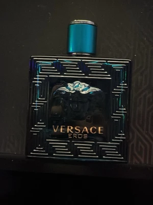 Versace Eros Eau de Toilette - Versace Eros parfym i en stilren, fyrkantig turkos glasflaska med grekiskt mönster och Medusa-huvud på framsidan. Flaskan har metallisk blå kork och guldtext. En ikonisk doft för dig som gillar exklusiva och moderna parfymer. Köptes för 1299kr från kicks nästan hel full.