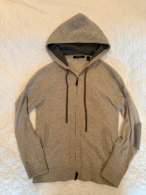 Kaschmir Zip Hoodie - Säljer denna riktigt feta Cashmere Zip Hoodien från Saks Fifth Avenue i Storlek M men passar även S. Tröjan är beige och har gråa detaljer. Passar till allt!  Skick 9/10 Storlek - S/M  Försöker skicka samma dag annars så snabbt jag kan!📦 Skriv vid fler frågor.