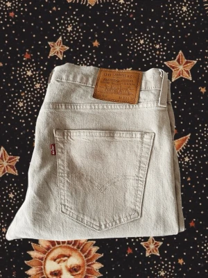 Beige Levi's 512 jeans - Säljer ett par klassiska beige Levi's 512 jeans i bomull. Modellen har rak passform, fem fickor och den ikoniska läderlappen bak i midjan. Perfekta för dig som gillar tidlös och clean stil. Levi's-röd etikett på bakfickan. Herrmodell men passar unisex