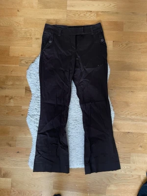 Mörkbruna kostymbyxor - Snygga mörkbruna kostymbyxor. Så snygga men tyvärr lite korta på mig (jag är ca 165 cm) står att de är stl 40 men sitter som stl 36. 