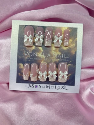 PearlKiss (S);Medium Square - Handgjorda press-on naglar i nuderosa och pärlemorvit french med pärlemorvita 3D-rosetter, pärldetaljer och subtil glittereffekt. Naglarna har en medium längd,  square form och elegant design som sticker ut. Perfekta för dig som vill ha något extra till naglarna.S: 15 mm, 11,5 mm, 12 mm, 11 mm, 9 mm  