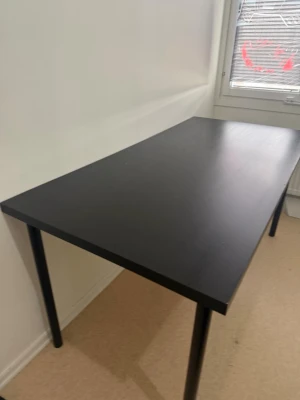 Matt bord - Stilrent svart skrivbord med rektangulär bordsskiva och fyra runda metallben. Perfekt för plugget, gaming eller som arbetsyta. Bordsskivan är slät och enkel att hålla ren. Passar bra i de flesta rum tack vare sin enkla design.