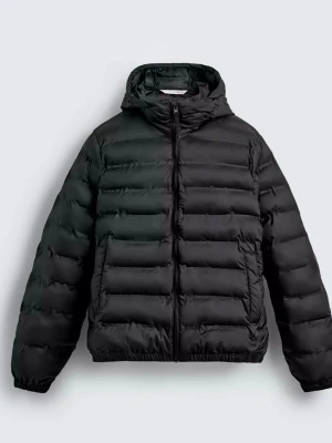 Zara pufferjacka med huva - Snygg svart pufferjacka med huva och dragkedja framtill. Jackan har breda, horisontella kanaler och två sidofickor. Tillverkad i ett glansigt material som ger en modern look. Perfekt för kalla vinterdagar när du vill hålla dig varm och stilren.