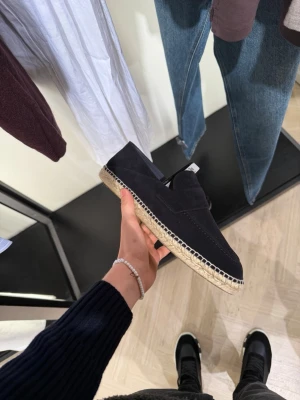 Svarta espadrilles Massimo Dutti  med flätad sula - Säljer ett par stilrena svarta espadrille Massimo Duttis  med ovandel i mocka och klassisk flätad sula i jute. Skorna har en enkel slip-on design och dekorativ söm längs kanten. Perfekta för en avslappnad och trendig look.