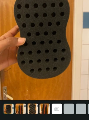 Svart twist-svamp för håret - Twist-svamp i svart skumgummi med hål för att skapa lockar eller twists i håret. Ergonomisk form och två röda linjer på sidan ger en snygg look. Perfekt för att fixa naturliga frisyrer snabbt och enkelt.