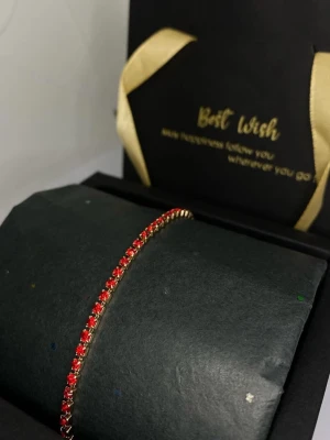 Guldarmband med röda pärlor - Snyggt armband i guldfärgad metall med små röda pärlor som ger en elegant och trendig look. Perfekt accessoar för att lyfta din outfit med lite färg. 