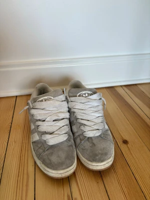 Grå Adidas sneakers i mocka - Säljer ett par grå Adidas Campus sneakers i mocka. Är lite smutsiga men annars i gott skick. 