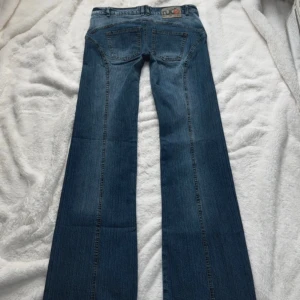 38|M low waist 00/90s retro jeans by love sex money - Midja: ~40cm. Innerbenslängd: ~87cm. Hel längd: ~107,5cm. Gren: ~20cm. Benbredd längst ner: ~24,5cm  Skitcoola utsvängda jeans men passar tyvärr inte mig pga är 179cm så de är lite väl lågmidjade på mig för min smak.