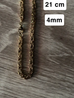 Guldpläterat kedjearmband 21 cm - Snyggt guldpläterat armband med kraftig kedjedesign och rektangulära länkar. Armbandet är 21 cm långt och 4 mm brett, perfekt för dig som gillar stilrena accessoarer med lite edge. Låset är av klassisk karbinmodell.