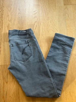 Dondup George Gråa - Gråa Dondups George Jeans, storlek W33. Jeansen är i helt okej skick, förutom loggan där bak så är dom bra skick 7.5/10. Hör av er för frågor!