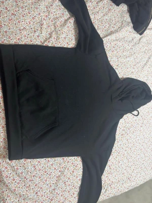 Svart hoodie med tryck 'Intense Feelings' - Svart hoodie med huva och känguruficka framtill. På ryggen finns ett stort grafiskt tryck med texten 'INTENSE FEELINGS' i vitt och gult samt en statybild. Hoodien har långa ärmar och dragsko i huvan. Perfekt för en chill och stilren look.