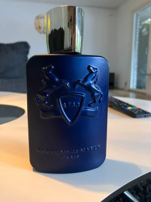 Parfums de Marly parfym LAYTON - Snygg parfym från Parfums de Marly i en matt mörkblå flaska med silverfärgat lock. Flaskan har ett upphöjt emblem med två hästar och texten '1743' samt 'PARFUMS DE MARLY PARIS'. Perfekt för dig som gillar exklusiva dofter och stilren design.