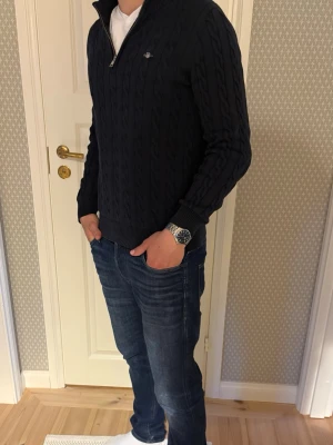 Mörkblå kabelstickad tröja Gant - Jag säljer nu en snygg mörkblå kabelstickad tröja från Gant med halv dragkedja och liten logga på bröstet. Tröjan har ribbade muddar och krage. Perfekt till jeans för en klassisk look. Tröjan är i 8,5/10 skick och varsamt använd. Passar S och jag är 180 cm lång och passar bra fortfarande. Skriv gärna frågor om ni funderar nåt! 