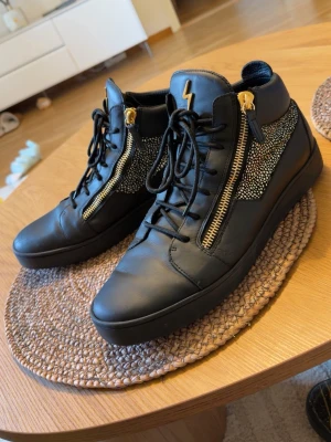 Giuseppe Zanotti Skor -  Äkta Giuseppe Zanotti Kriss high-top sneakers i svart läder med guldiga dragkedjor och glittriga sidopaneler
