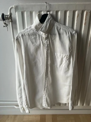 Replay skjorta - Klassisk vit skjorta med unik hög krage och bröstficka. Skjortan har knäppning framtill och långa ärmar med manschetter. Perfekt för dig som gillar stilrena och minimalistiska plagg. Materialet ser ut att vara bomull eller linne.