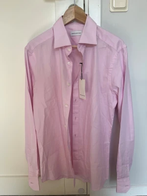 Rosa skjorta från These Glory Days - Säljer en stilren rosa skjorta från These Glory Days i storlek L. Present som jag inte vågade be om kvitto för. Aldrig använd, och prislappen sitter kvar.
