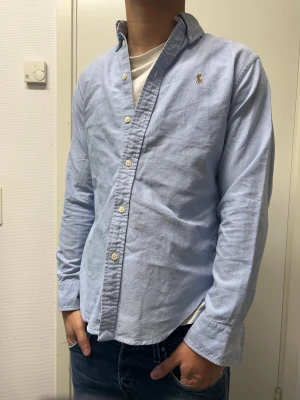 Ralph Lauren skjorta  - Snygg ljusblå skjorta från Polo Ralph Lauren. Storlek S men passar XS. Väldigt bra skick. Modellen är 173cm, 64kg. Pris kan diskuteras!!
