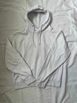 Vit hoodie med huva från Lager 157 - Klassisk vit hoodie med huva och dragsko. Tillverkad i mjukt bomullsmaterial med ribbade muddar vid ärmslut och nederkant. Perfekt för en clean och avslappnad stil. Inga synliga loggor eller tryck, enkel och stilren design. Diskuterar gärna pris! ✨