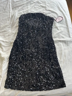 Svart paljettklänning axelbandslös - Snygg svart axelbandslös kortklänning täckt med glittriga paljetter. Prislappen är kvar💞💞