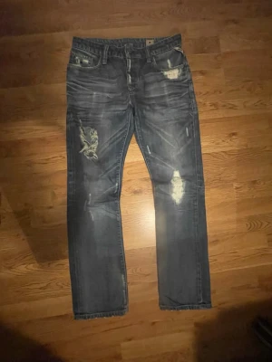 Vintage jeans - Säljer desssa jack and jones jeans i blå fade med slitningar. Modellen heter  clark vintage jos. Passar 175-185. Straight fit Storlek 32/32
