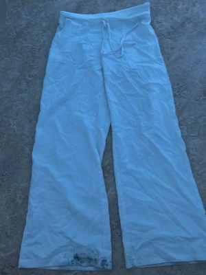 Vita vida linnebyxor - Vita linnebyxor med bred passform och dragsko i midjan. Byxorna har raka ben och är tillverkade i ett mjukt, bekvämt tyg. Perfekta för chill dagar hemma eller när du vill ha en avslappnad stil. Det är olja längst ner på byxorna.