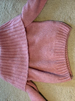 Rosa stickad foldover tjocktröja  - Mysig rosa stickad tröja med bred ribbad polokrage och långa ärmar. Tröjan har en avslappnad passform och är tillverkad i ett mjukt garn som känns skönt mot huden. Perfekt för kyliga dagar och enkel att styla till jeans eller kjol.