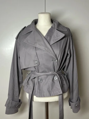 Kort trenchcoat med band Gina tricot - Superfin trenchcoat med snöre från Gina. Storlek s. Nypris 700kr, slutsåld.  Köp sker via köp nu, jag postar inom 24h. Kvar tills markerad såld