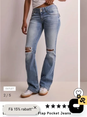 Ljusblå bootcut jeans med slitningar - Säljer ett par ljusblå bootcut jeans med slitningar över knäna och snygga ficklock bak. Jeansen har klassisk femficksmodell, låg midja och stängs med dragkedja och knapp. Perfekta för en avslappnad och trendig look.