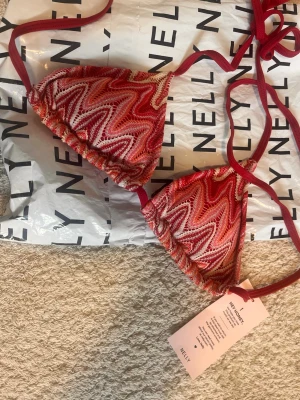 Missoni bikiniöverdel från Nelly - Säljer en snygg trekantsbikini från Nelly med missoni-mönster i olika röda, rosa och orange toner. Bikinin har knytband i nacken och ryggen, vilket gör den enkel att justera. Perfekt för lata dagar på stranden eller poolen! OBS! Helt nytt skick med prislapp kvar, och slutsålt på hemsidan, därav priset. För snabb inlämning välj gärna PostNord ❤️