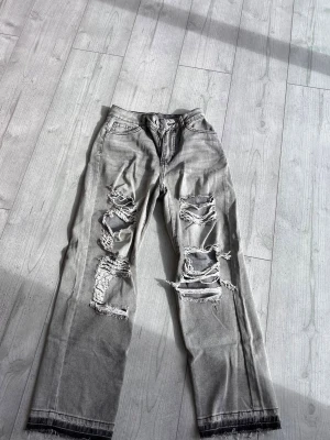Gråa jeans med hål - Säljer dessa gråa jeans med hål i pågrund av att de inte används längre. Har använt de 1 gång. De är raka i benen men ändå baggy. Är i storlek xs/s. :).    