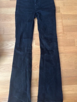 Svarta bootcut jeans - Säljer ett par svarta bootcut jeans med klassiska fickor bak och fram. Jeansen har hög midja och är tillverkade i ett stretchigt denim-material som sitter snyggt. Perfekta för dig som gillar en tidlös och cool look.