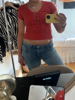 Röd/orange topp med snörning - Säljer en röd/orange topp från Bik Bok med snörning framtill och v-ringad hals. Superfin sommartopp!!!