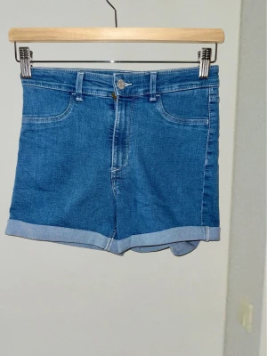 Stretchiga jeansshorts från &DENIM –XXS - Klassiska jeansshorts i en snygg mellanblå tvätt! ☀️ Hög midja, fyra fickor och trendigt uppvikta benslut. Tack vare stretchen är de superbekväma och perfekta för aktiva sommardagar. Ett oumbärligt basplagg! ​Märke: &DENIM (H&M) ​Storlek: 146 XXS ​Material: Bomullsmix med stretch