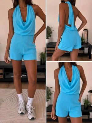 Turkos jumpsuit med draperad hals - Cool turkos jumpsuit med draperad halsringning och öppen rygg. Materialet är lätt och har en krinklad struktur. Jumpsuiten har korta ben och knytdetalj i nacken som ger en snygg look. Perfekt för dig som vill sticka ut med färg och stil.
